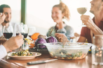 Happy friends eating vegetarian food and drinking red wine - Vegan family dining fresh vegetables in farmhouse - Healthy people lifestyle and cooking culture concept