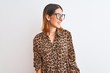 © Krakenimages.com - Beautiful redhead woman wearing glasses and elegant animal print shirt over isolated background looking away to side with smile on face, natural expression. Laughing confident.