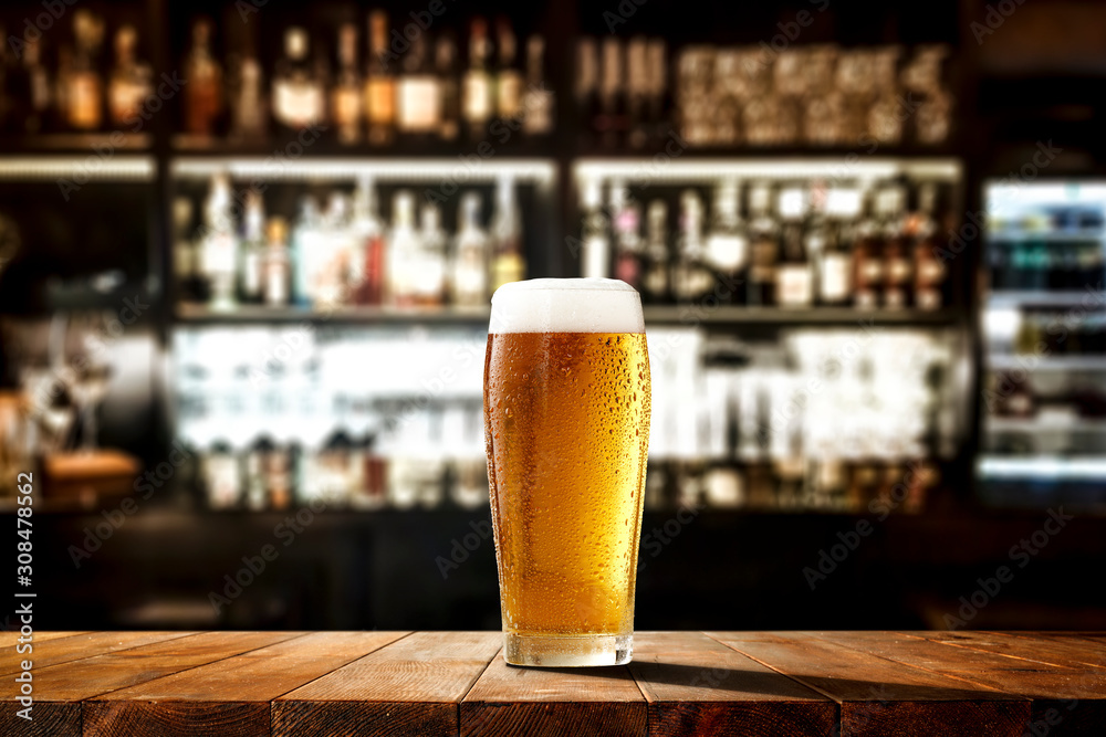 Glass of beer on wooden board and blurred bar background.Free space for your decoration.  - obrazy, fototapety, plakaty 