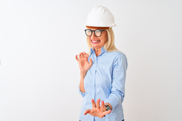 Middle age architect woman wearing glasses and helmet over isolated white background disgusted expression, displeased and fearful doing disgust face because aversion reaction. With hands raised