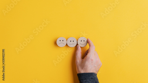 Fotografía Male hand choosing a smiling face option from the row of three choices