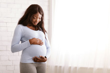 Peaceful Pregnant Afro Woman Hugging Her Tummy At Home