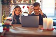 © Krakenimages.com - Young beautiful couple sitting using laptop around christmas decoration at home with hand on head for pain in head because stress. Suffering migraine.