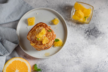 Wall Mural - stack of homemade pancakes with orange and mint. healthy breakfast. gray concrete background, horizontal image, copy space