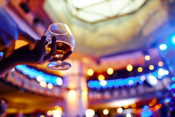 woman holds a glass of whiskey in a nightclub on the background of beautiful lights