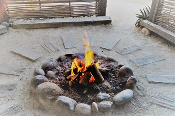 Sticker - Beautiful high angle shot of a burning bonfire surrounded by sand wood and stones