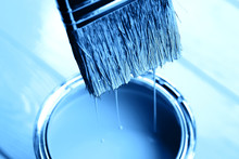Blue Paint Is Dripping From Brush Into Open Can On Freshly Painted Wooden Background. Renovation Concept. Macro.