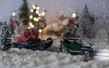 Miniature Classic Car Carrying A Christmas Tree And Gifts On Snowy Road In Winter Background