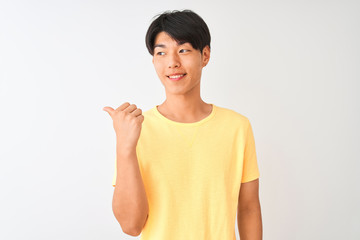 Wall Mural - Chinese man wearing yellow casual t-shirt standing over isolated white background smiling with happy face looking and pointing to the side with thumb up.