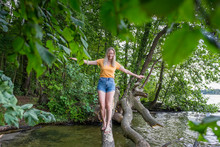 Smiling Woman Balancing On A Tree Trunk At Lakeshore