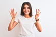 © Krakenimages.com - Young beautiful woman wearing casual t-shirt standing over isolated white background showing and pointing up with fingers number nine while smiling confident and happy.