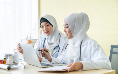 Two woman muslim doctors using a digital tablet, discussing diagnosis deadly disease in Specialized clinics