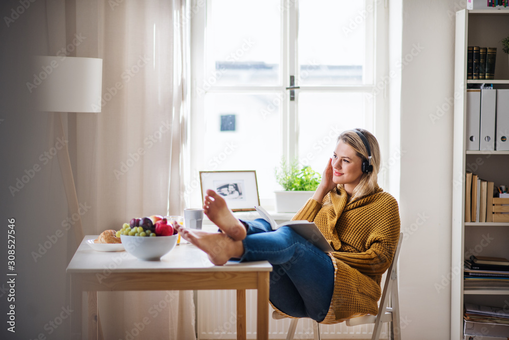 Young woman sitting at the table indoors at home, reading a book. Stock ...