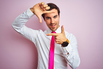 Canvas Print - Young handsome businessman wearing shirt and tie standing over isolated pink background smiling making frame with hands and fingers with happy face. Creativity and photography concept.