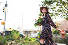 Happy Woman Walking Through Urban Garden With Flowers
