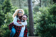 Happy and cheerful caucasian people couple having fun together in friendship and relationship - middle afe woman and man - carrying the lady in the outdoor leisure activity with green forest