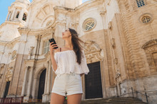Student With A Phone In Light Summer Clothes On The Background Of The Cathedral