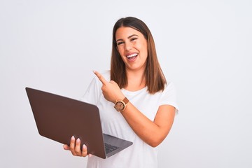 Sticker - Beautiful young woman working using computer laptop over white background with a big smile on face, pointing with hand finger to the side looking at the camera.