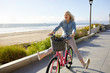 © Cavan Images - Cheerful senior woman screaming while riding bicycle on road against sky during sunny day
