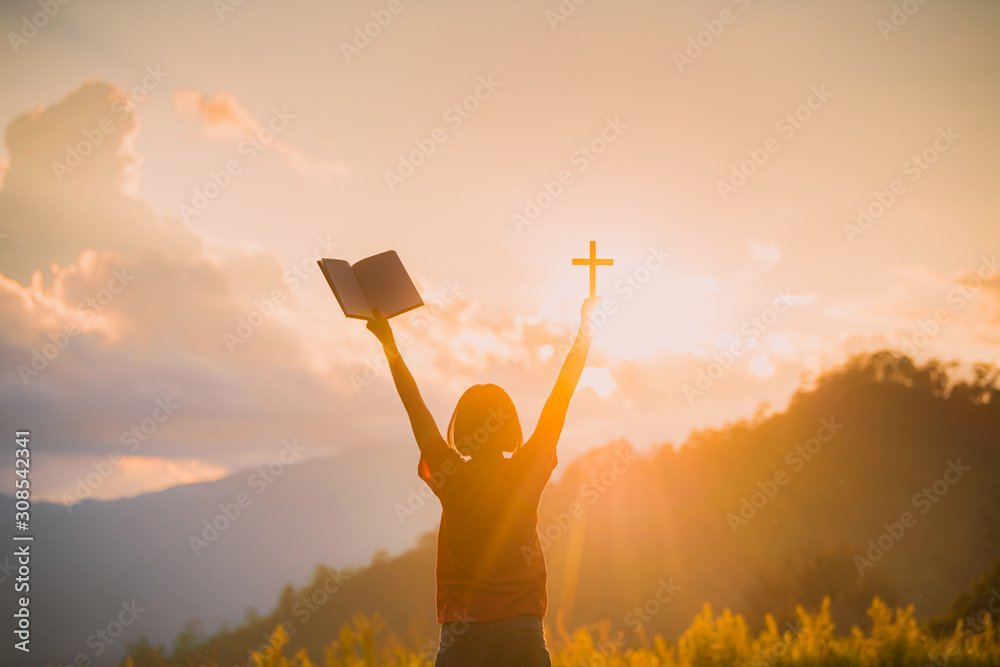 The silhouette of a woman's hand, praying spiritually over the sun ...