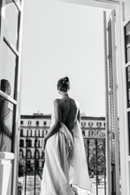 A Girl Resting At The Hotel Stands In The Opening Of An Open Balcony, Wrapped In A Sheet. The Naked Back Is Turned To The Camera, Photo Black And White