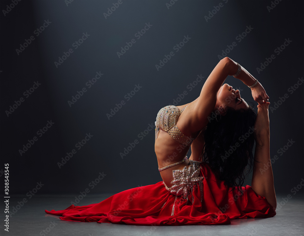 beautiful black-haired girl in red ethnic dress dancing oriental dances leaning back - obrazy, fototapety, plakaty 
