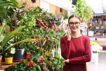 Wall Mural - Female business owner talking on mobile phone in flower shop