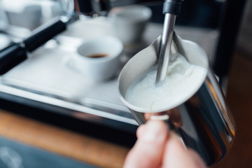 steam frothing milk under pressure from a coffee machine in pitcher