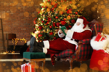 Poster - Santa Claus reading book near decorated Christmas tree indoors