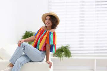 Poster - Beautiful woman in casual outfit on sofa indoors. Space for text