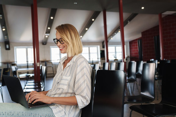 Canvas Print - Photo of laughing young woman working on laptop and cellphone