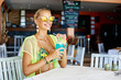 Summer portrait of a beautiful blonde woman drinking cocktail in an outdoor beach bar