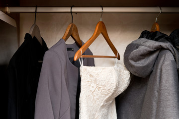 Wall Mural - view of the open wardrobe, in which, among gray clothes, the bride s elegant dress hangs