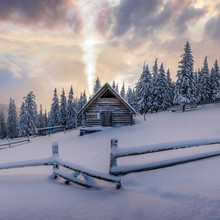 Fantastic Winter Landscape With Wooden House In Snowy Mountains. Smoke Comes From The Chimney Of Snow Covered Hut. Christmas Holiday Concept
