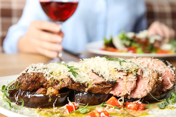 Delicious roasted meat and blurred woman on background, closeup