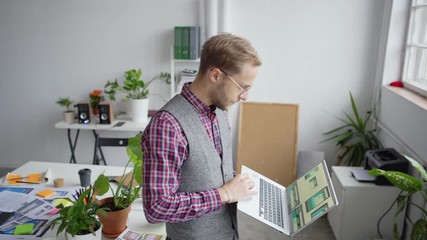 Wall Mural - tilt up zoom out of printed app interface samples on office desk and confident entrepreneur standing