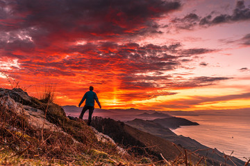 A young man in the incredible orange sunset on the winged Mount Jaizkibel of San Sebastian. Basque Country