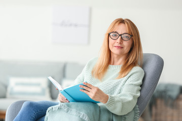 Wall Mural - Beautiful mature woman reading book at home