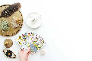 tarot cards in woman's hand on a white background. reading, feathers, crystals, tea.