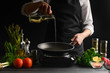 © Anton - Chef pouring oil on a frying pan, freezing in motion. On a background with ingredients. Homemade fish recipes, gastronomy