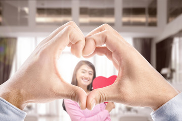 Wall Mural - Man hands with the shape of the heart showing his girlfriend holding a red heart