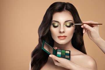 Makeup artist applies eye shadow. Beautiful woman face. Perfect makeup. Make-up detail. Beauty girl with perfect skin. Nails and manicure. Eye shadow palette