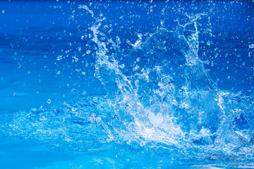 splashes of clear blue fresh water in pool, air bubbles, water drops, sea wave on blue background wi
