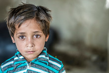 Closeup Of A Poor Staring Hungry Orphan Boy In A Refugee Camp With Sad Expression On His Face And His Face And Clothes Are Dirty And His Eyes Are Full Of Pain