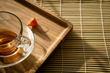 Cup of tea on the bottom and a flower of pineapple on a wooden tray.