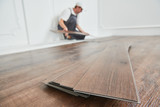 Fototapeta  - worker laying vinyl floor covering at home renovation