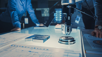 Leinwandbilder - Close Up of a Futuristic Robotic Arm Picking Up a Metal Object and Moving It. Team of Engineers Following This Advanced Process. They are in a High Tech Research Laboratory with Modern Equipment.