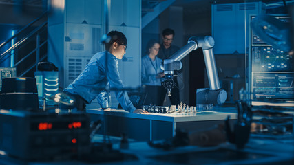 Fototapete - Professional Japanese Development Engineer is Testing an Artificial Intelligence Interface by Playing Chess with a Futuristic Robotic Arm. They are in a High Tech Modern Research Laboratory.