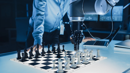 Poster - Close Up Shot of a Artificial Intelligence Operating a Futuristic Robotic Arm in a Game of Chess Against a Human. Robot Moves a Pawn. They are in a High Tech Modern Research Laboratory.