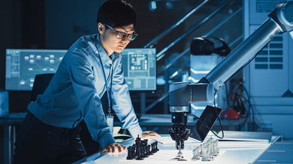 Poster - Professional Japanese Development Engineer is Testing an Artificial Intelligence Interface by Playing Chess with a Futuristic Robotic Arm. They are in a High Tech Modern Research Laboratory.